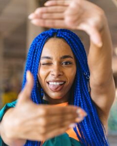 a person with blue braids making a frame with her hands